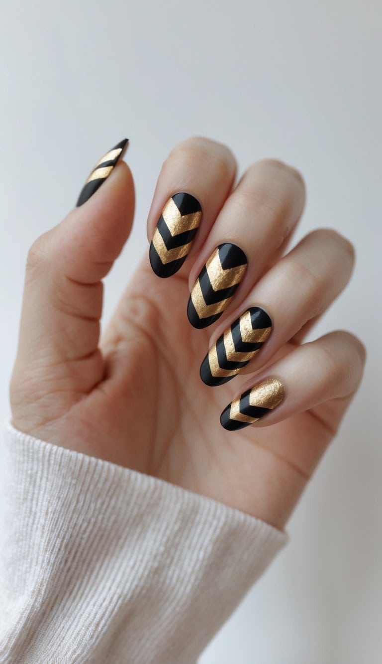 Shown on a relaxed hand, matte black nails are detailed with bold gold chevron lines, highlighting a Graduation Nail Art Idea that feels strong, graphic, and celebratory.