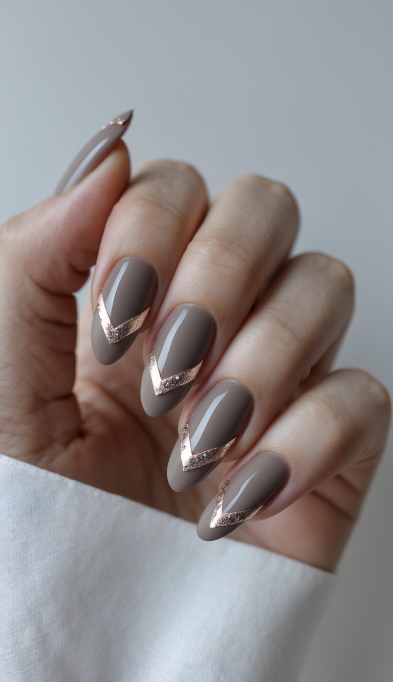 Nails painted in creamy taupe with bold, reflective rose gold V-shaped tips—an architectural, high-concept sophisticated nail art idea for modern minimalists.
