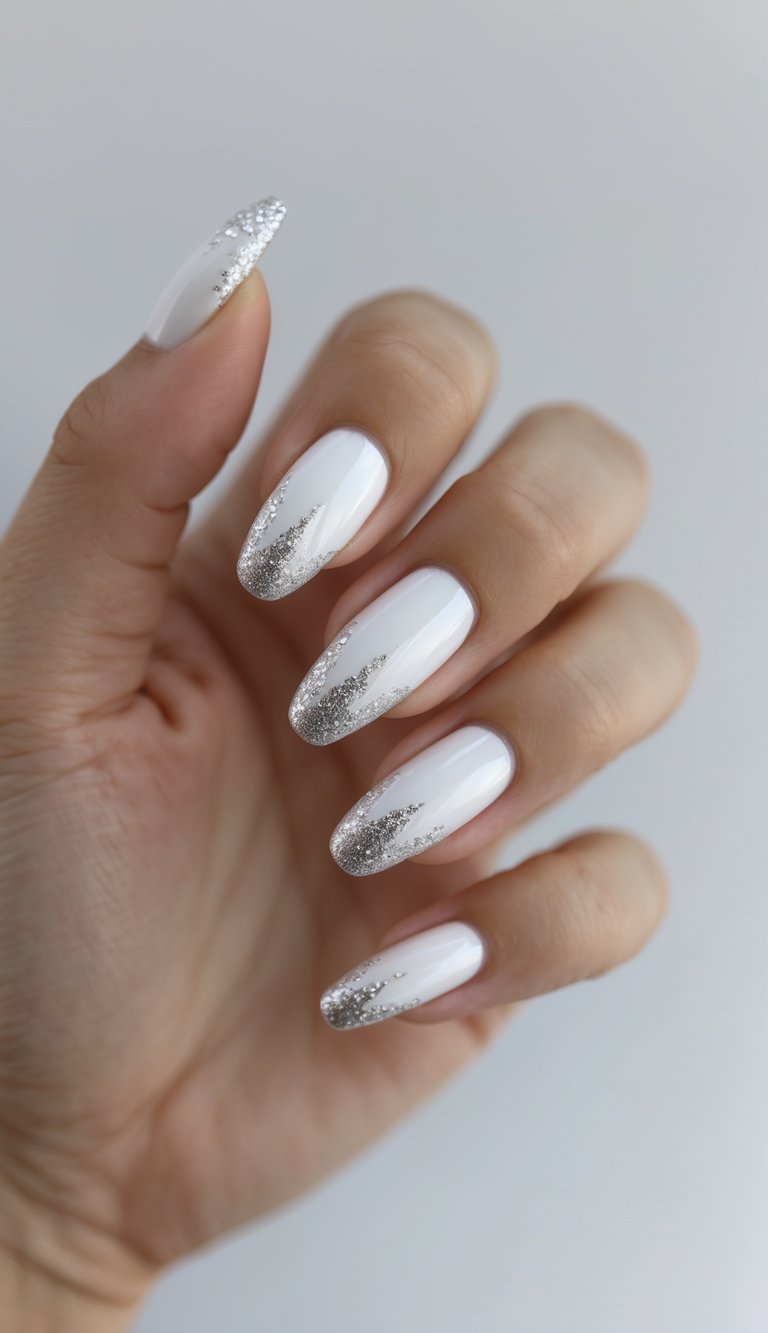 Close-up of a hand with glossy white nails and sparkly silver tips against a white background.