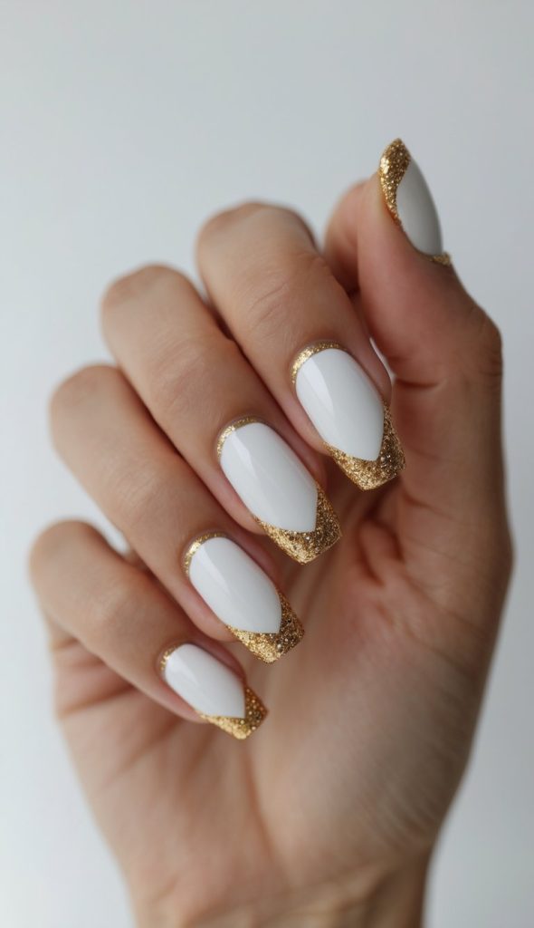 Angled view of a hand displaying colored French nail art idea with white manicure, curved gold glitter tips, glossy finish, clean cuticles, and minimal background.