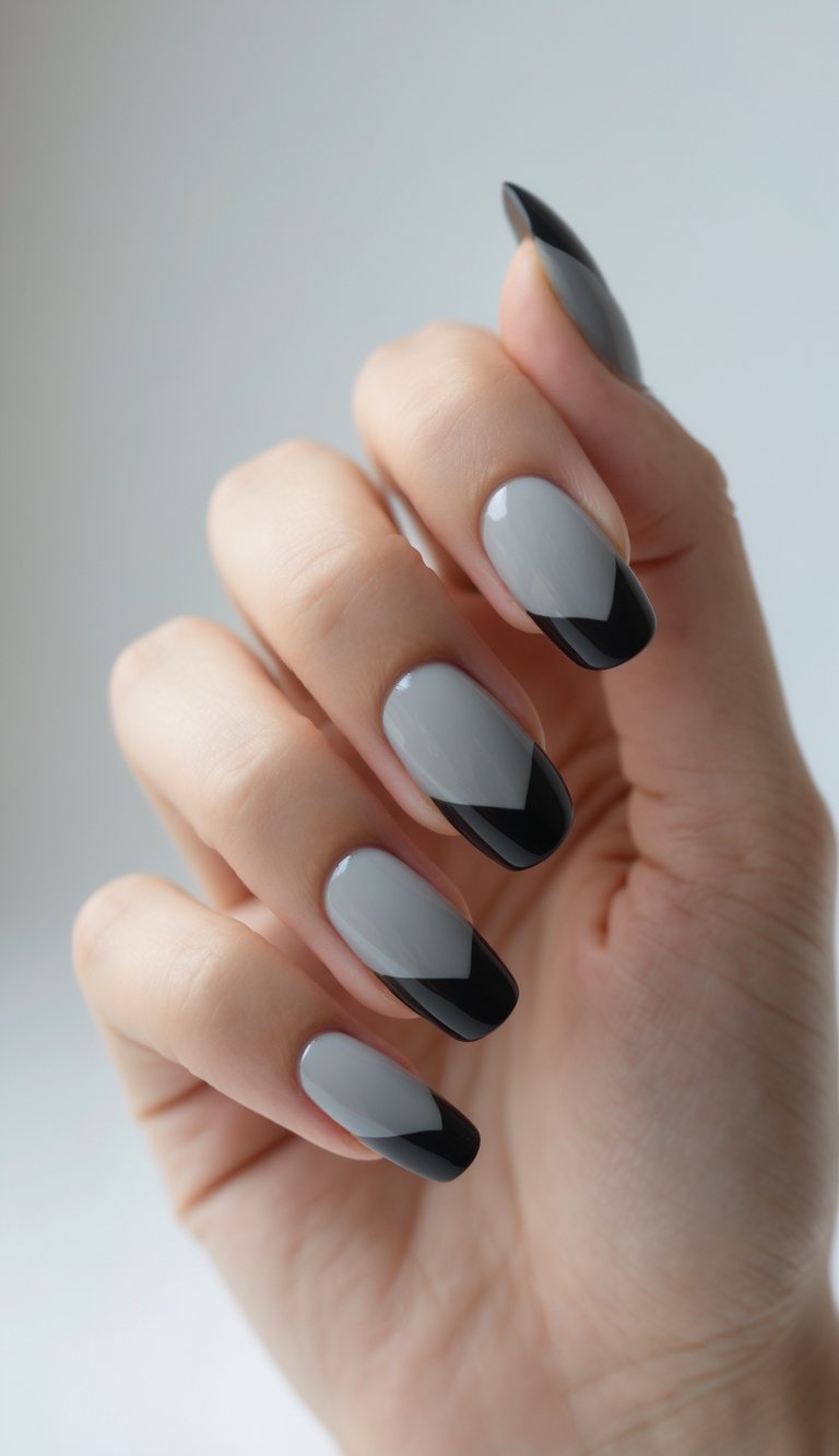 Soft gray nails featuring bold black angled tips offer a minimalist yet striking vibe