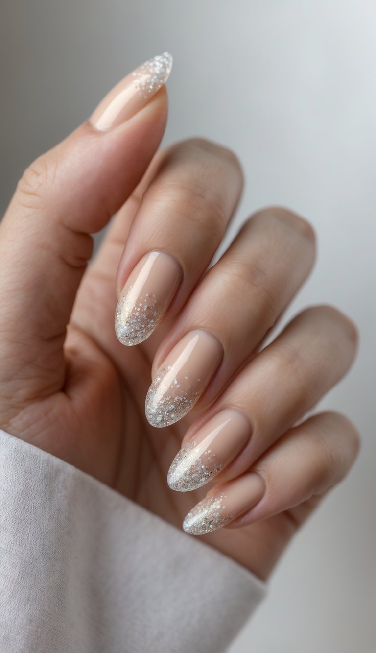 Close-up of one hand with manicured nails featuring champagne color and soft glitter gradient on a white background.
