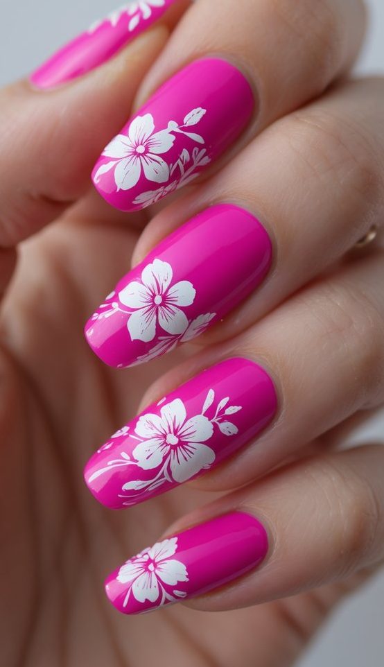 Close-up of a hand showcasing a fuchsia nail art idea with glossy hot pink nails decorated with bold white flower prints, combining playful detail and strong contrast.