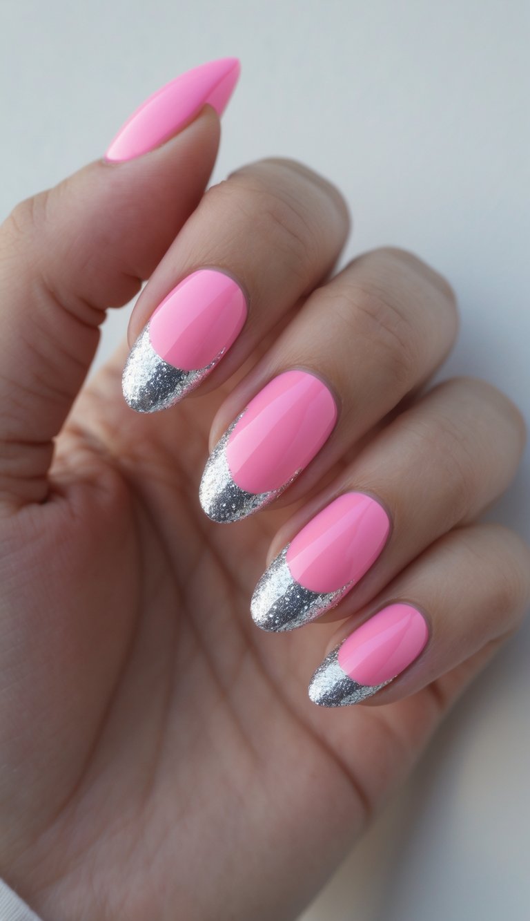 Seen from a natural angle, a hand reveals a pink and silver nail art idea featuring glossy pink nails highlighted by silver glitter at the tips.