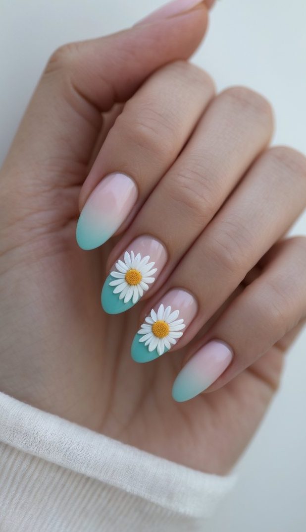 Hand with medium almond nails in a pale blush-to-teal gradient, featuring realistic 3D daisy accents on two fingers, captured in natural lighting for a minimal floral look