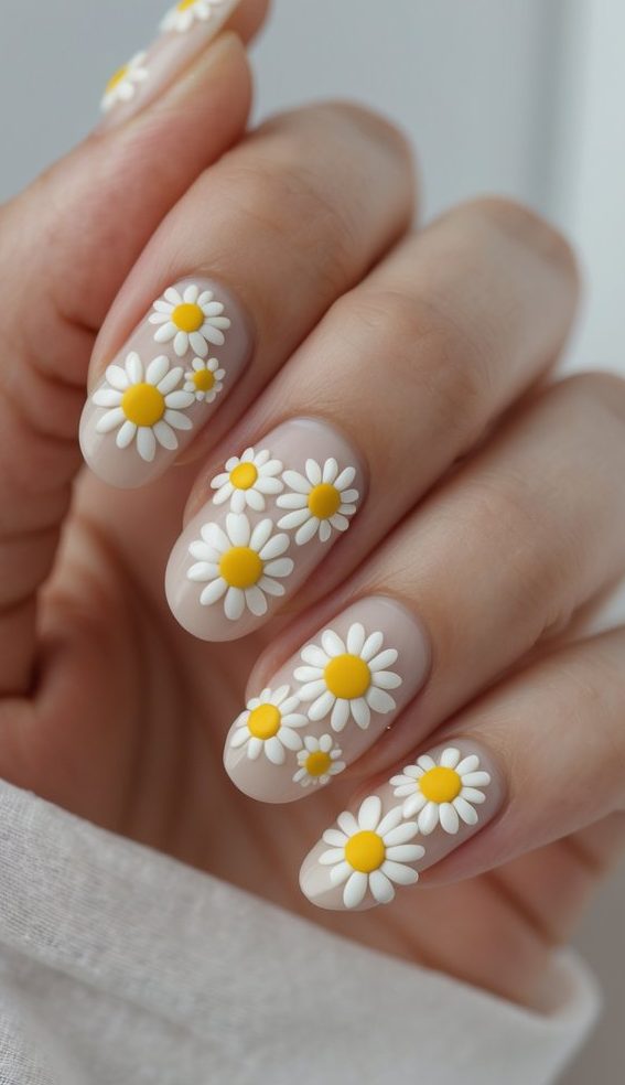 Editorial-style manicure with nude polish and layered 3D white daisies in various sizes, arranged like overlapping blossoms for a bouquet-inspired nail design