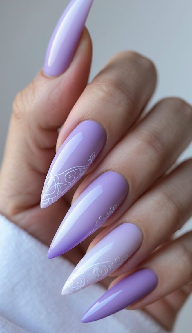 Stiletto nail art idea with soft lilac hues and intricate white scrollwork on glossy, pointed nails