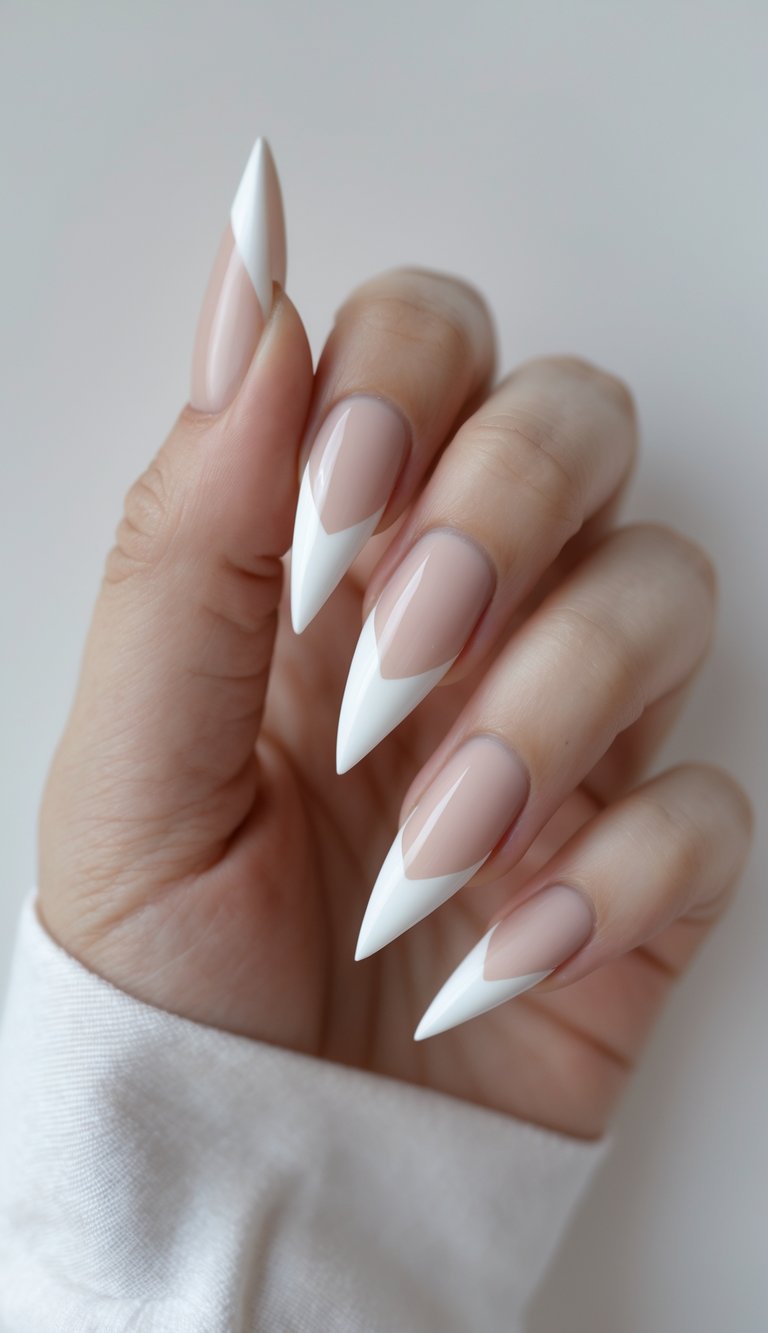 Stiletto nail art idea with sheer nude base and clean white V-shaped French tips for an elegant, sculpted design