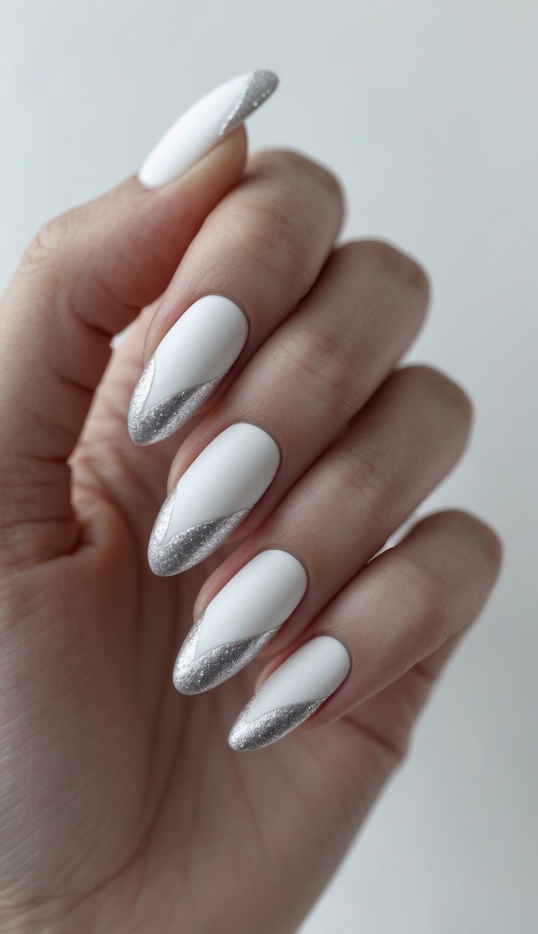 Elegant hand featuring almond-shaped nails with matte white polish and silver glitter waves at the tips—a bold engagement nail art idea for modern brides.