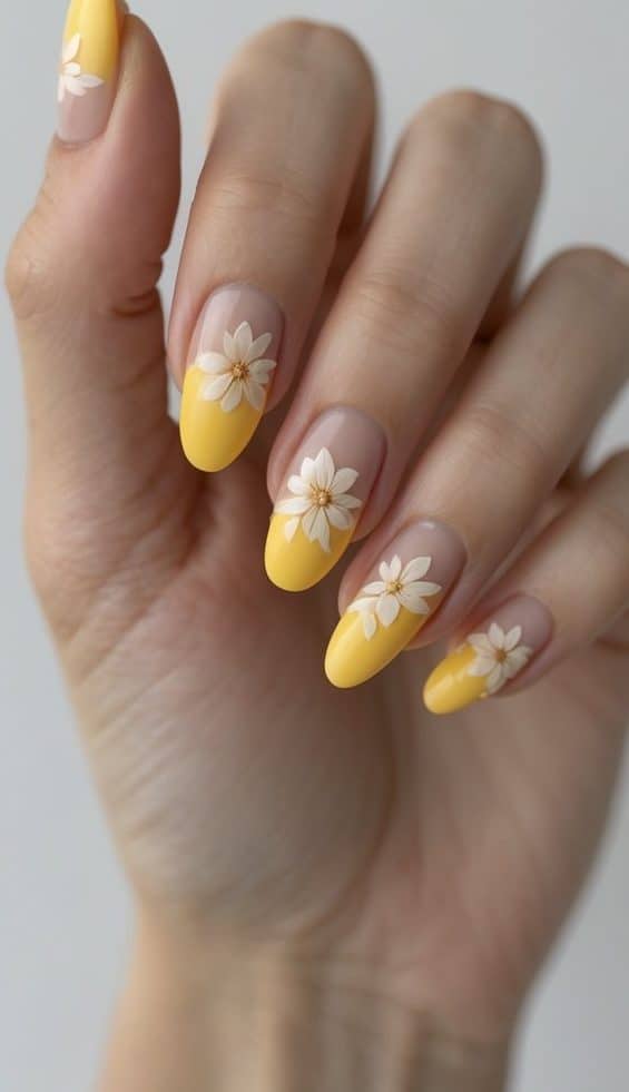 Close-up of hands with almond nails featuring yellow French tips and beige daisy accents, creating bright and happy march nail art ideas.