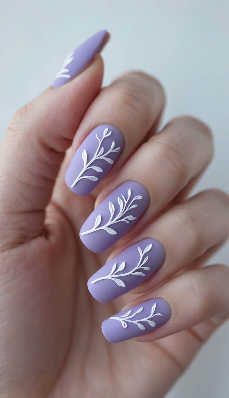Close-up of hands with matte lavender nails and delicate white leaf branch accents, blending elegance with nature-inspired march nail art ideas.