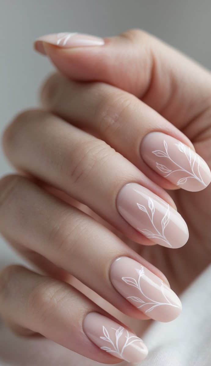 Hand with long sheer nude nails decorated with white leaf line art — minimalist romantic nail art ideas