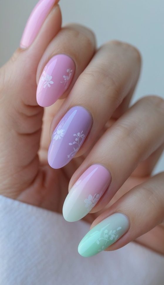 Pastel ombré manicure featuring a viral nail art idea with blended pink, purple, and mint shades accented by fine white floral patterns.