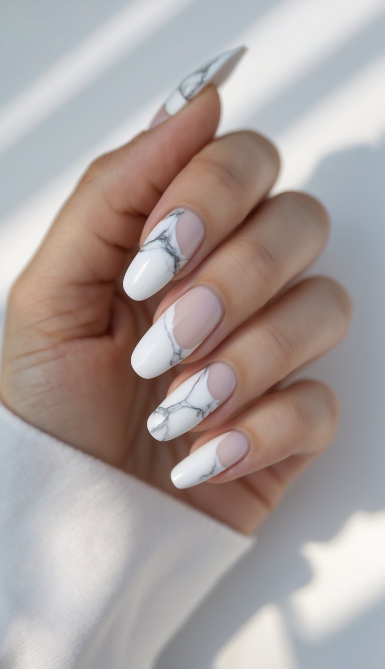 Hand with almond nails showing a white French tip nail art idea featuring marble-veined tips over a nude base with smooth curved accents