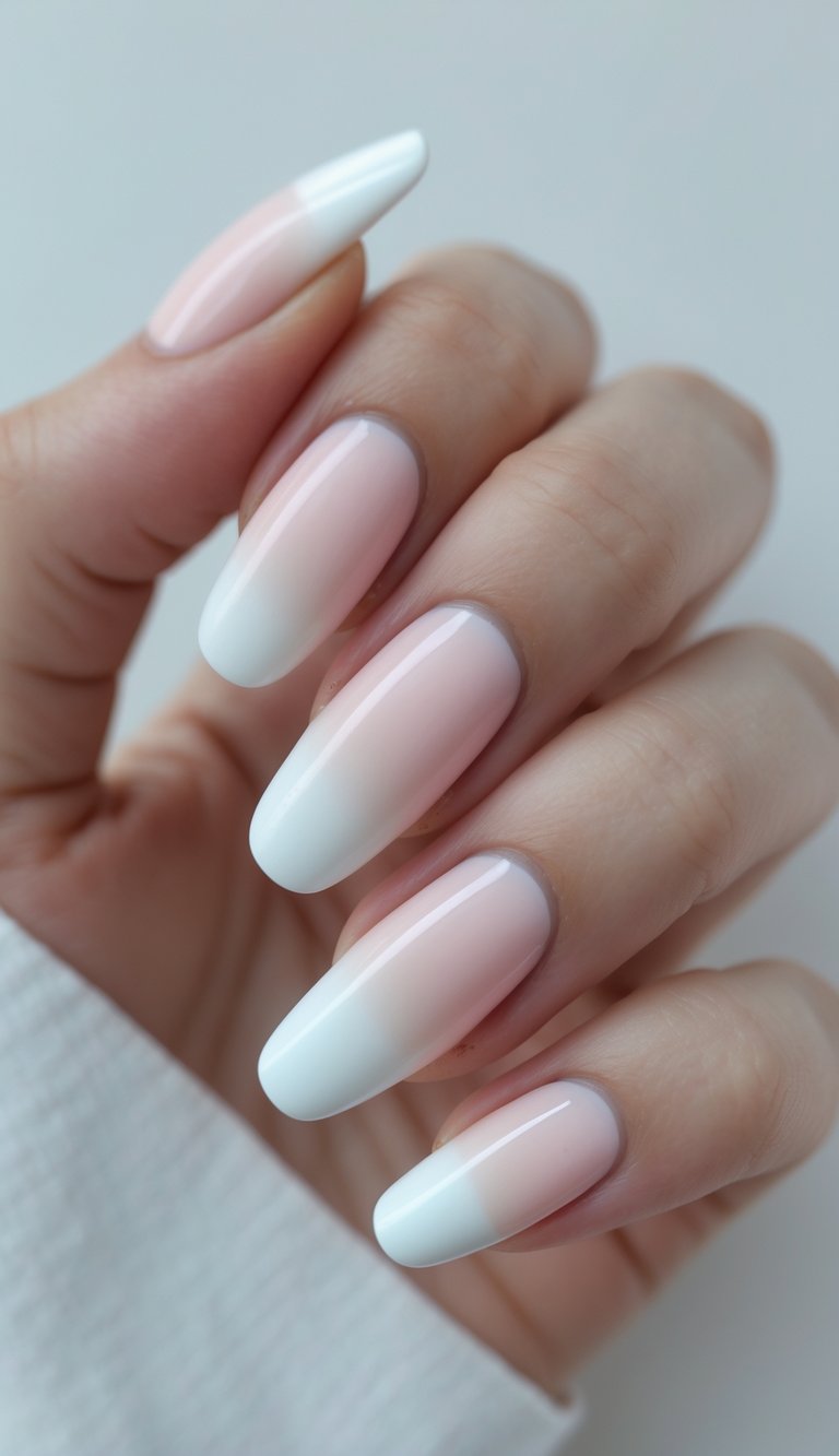 Close-up of long, almond nails showcasing a white French tip nail art idea with smooth blush-to-white gradient over a neutral base