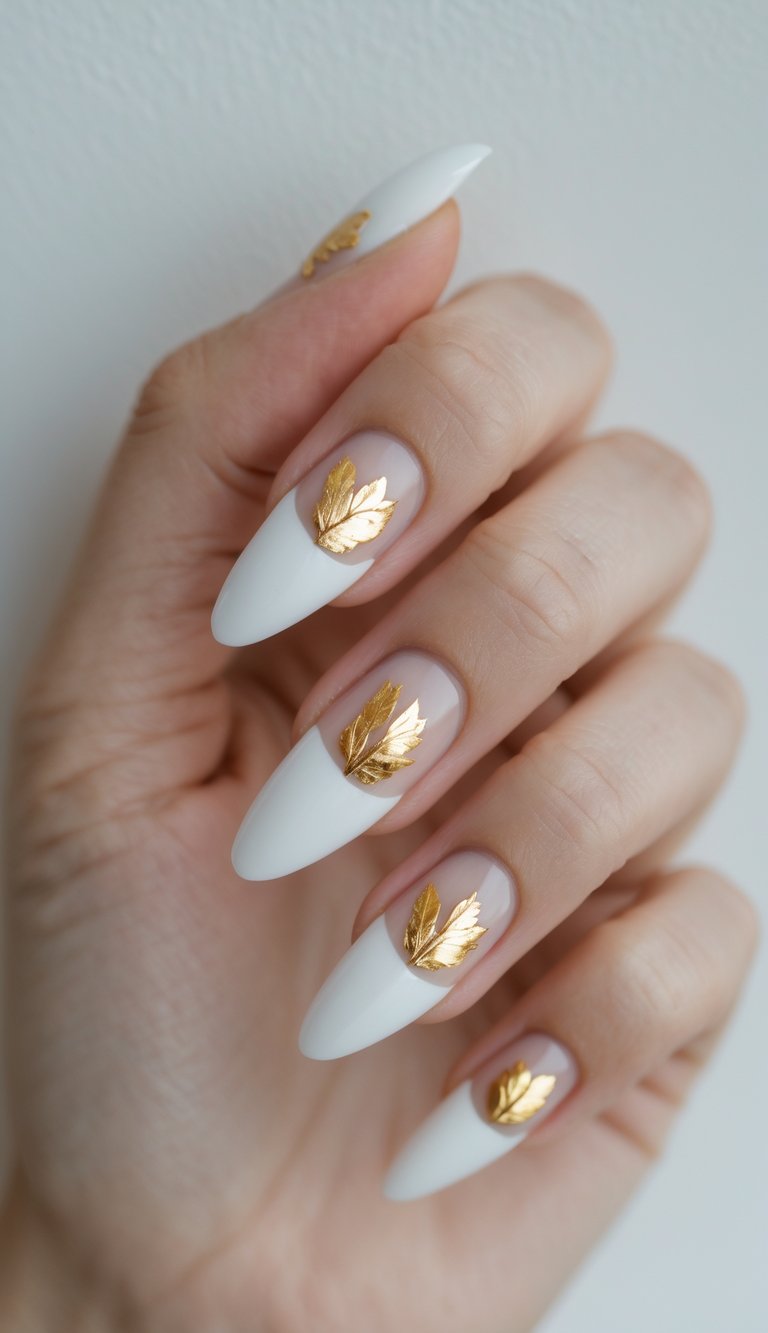 A hand with almond-shaped white French tip nail art idea accented by gold foil leaf decals over a sheer nude base