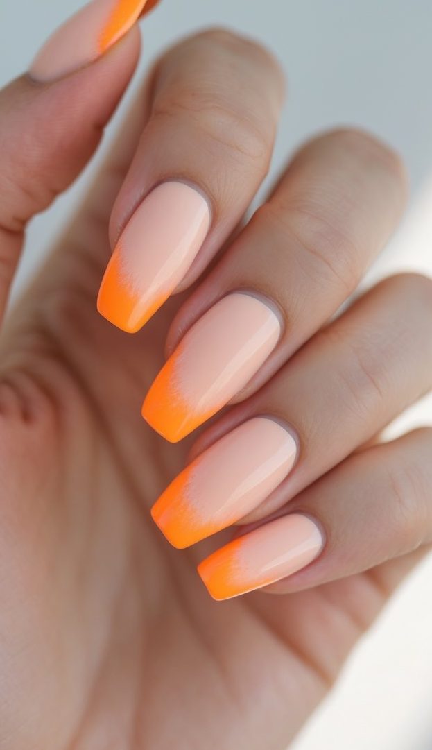 Sheer nude nails transitioning into bright neon orange French tips, glossy finish, seamless ombré blend, and a bold colored French nail art idea design.