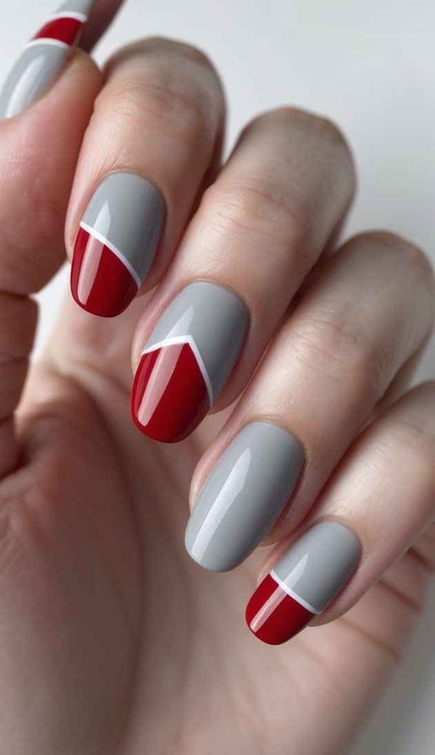 This image captures a hand wearing glossy gray and deep red nails, designed with curved white separators that create a structured two-tone nail art look.