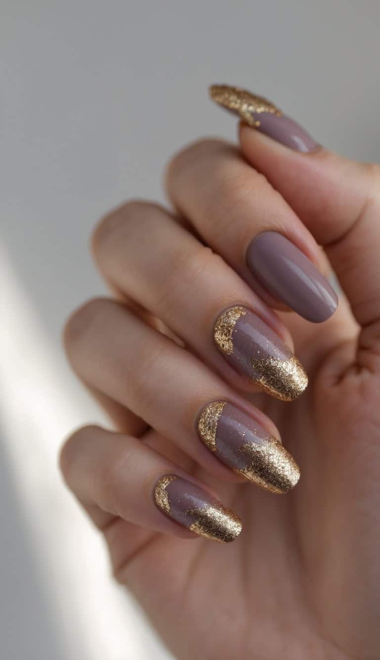 A softly lit hand displays almond-shaped nails painted mauve with gold glitter concentrated at the tips, showcasing polished two tone nail art ideas with a luxe finish.