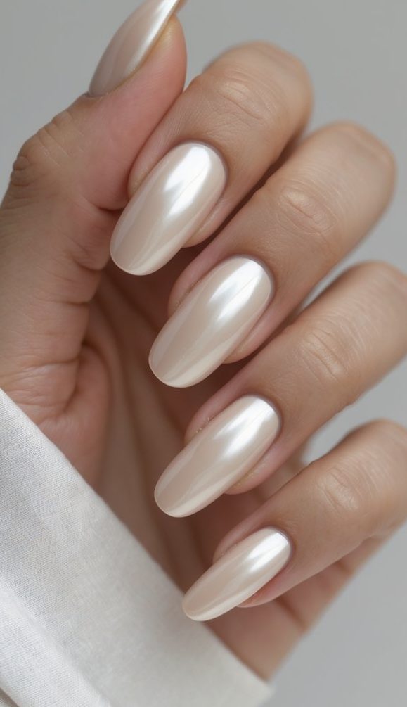 Close-up of fingers showing creamy champagne nails with a high-gloss pearlescent shine—this glossy nail art idea offers a graceful, luminous look.