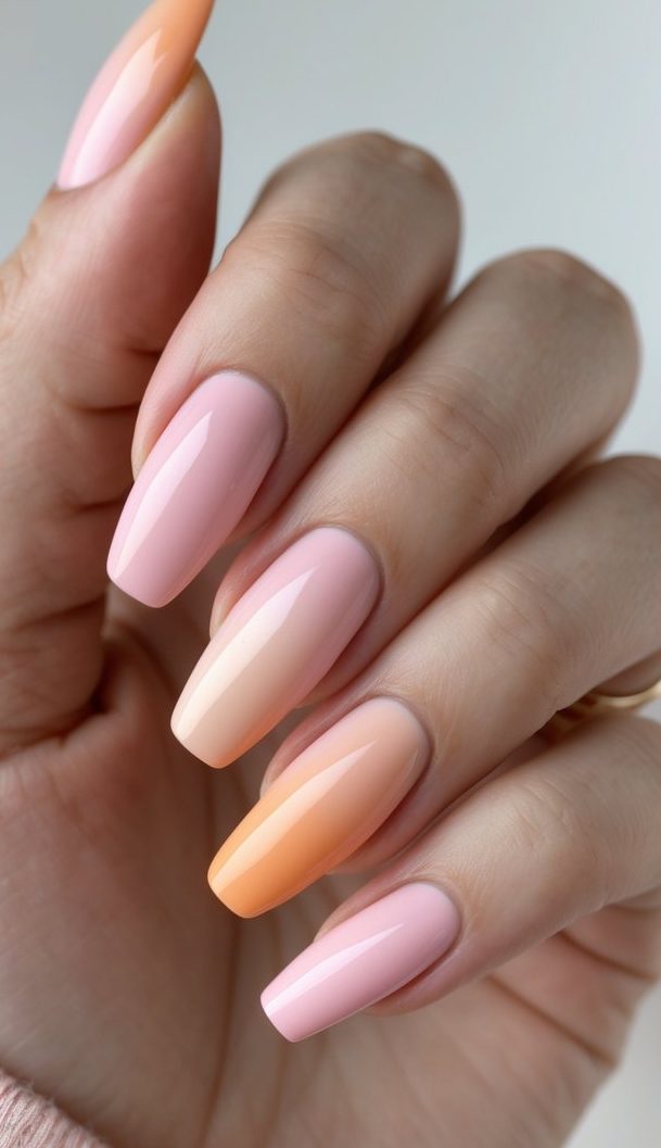 Feminine hand with softly squared nails featuring an ombre French nail art idea that gently shifts from baby pink to pale orange.
