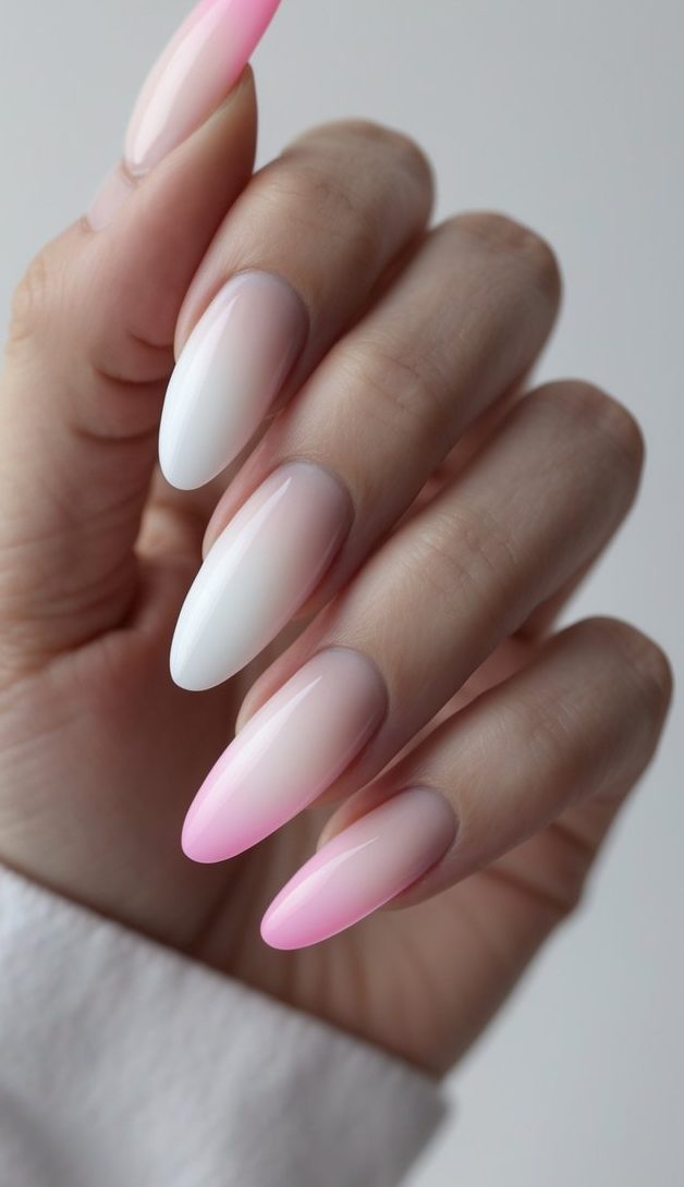 Close-up of fingers with a minimalist ombre French nail art idea in white and pink tones on glossy almond-shaped nails.