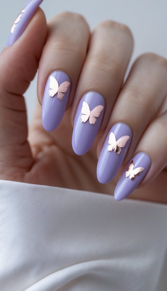 Close-up of a hand showing a foil nail art idea using lavender base polish and metallic butterfly foil decals on each nail.