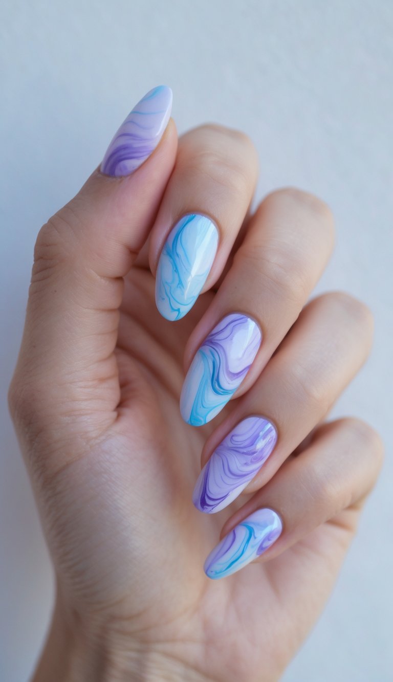 Hand with pastel purple and blue nails styled in a marble nail art idea, combining soft, curved swirl patterns on a smooth, glossy finish