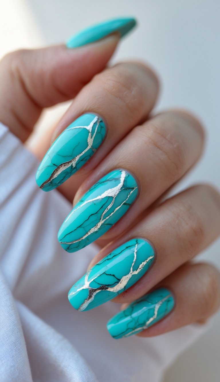 Close-up of fingers with glossy turquoise nails in a marble nail art idea, detailed with gold foil-like cracks for a bright and stylish summer look