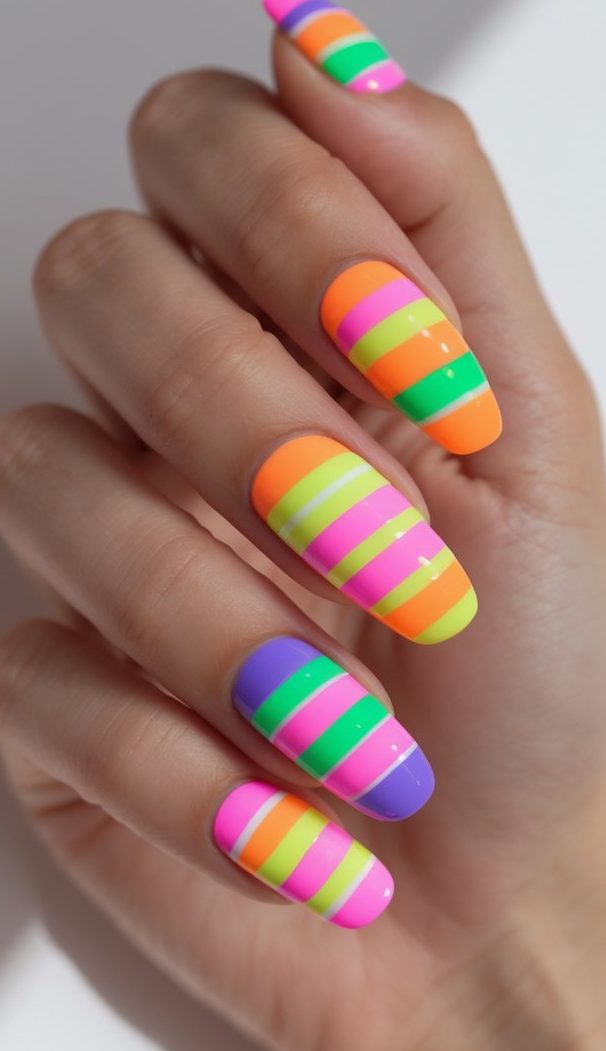 A close-up of fingers with multi-colored neon stripes across shiny oval nails, showcasing a lively stripe nail art idea perfect for summer or party looks.