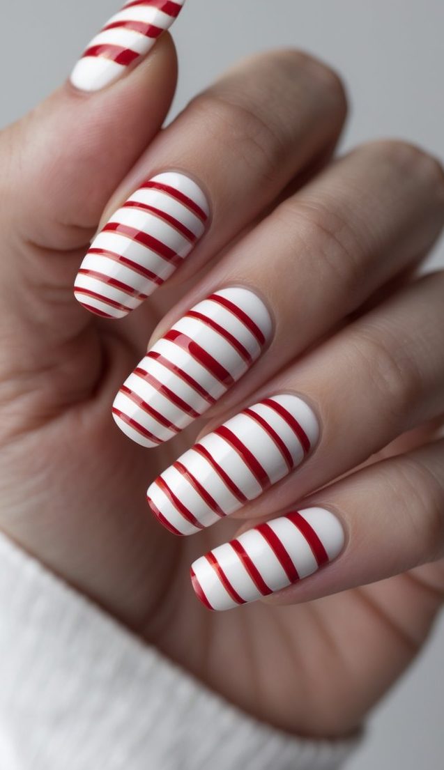 Stripe nail art idea featuring white almond-shaped nails detailed with clean, glossy red horizontal stripes for a bold and minimalist holiday-ready design.