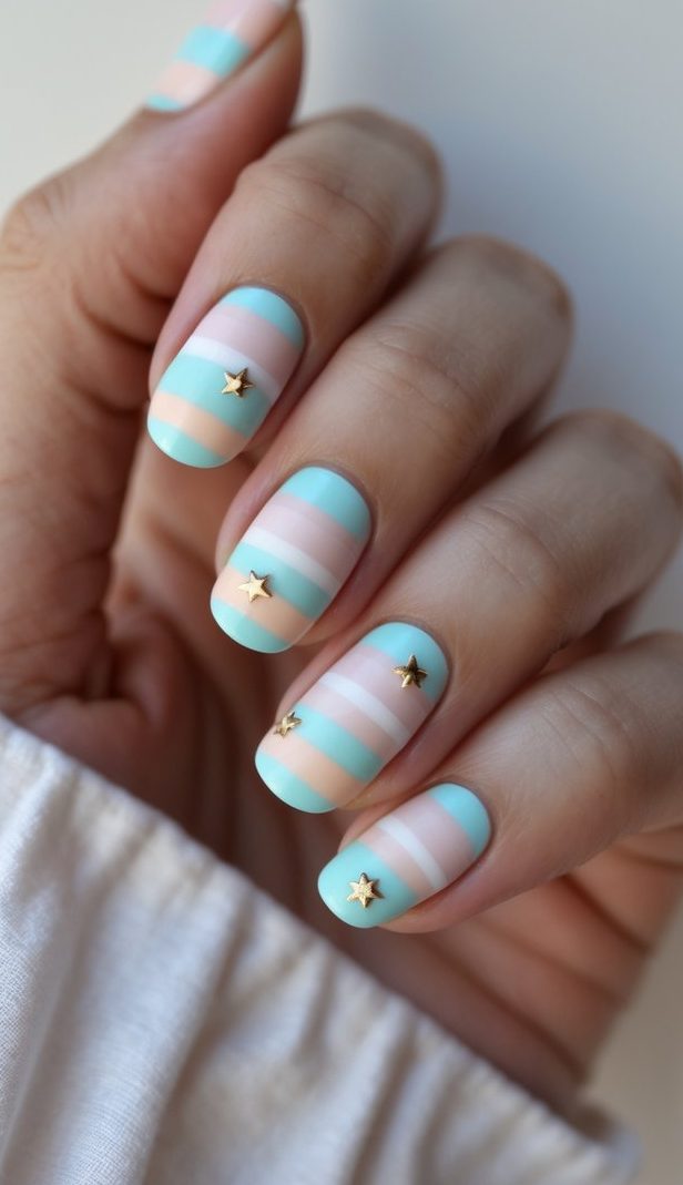 Stripe nail art idea with matte pastel stripes in blush, aqua, and nude shades, finished with tiny gold star decals for a whimsical and playful effect.