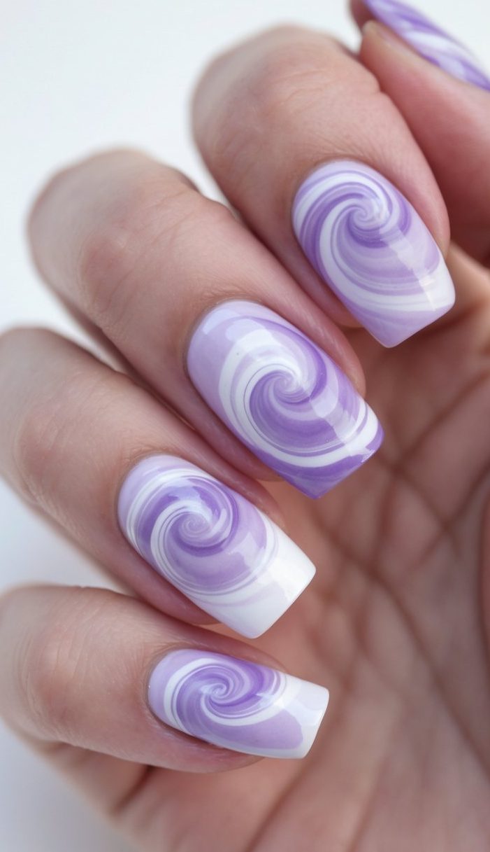 Swirl nail art idea on square-shaped nails with bold violet and crisp white spiral details, held in a relaxed hand against a light background.