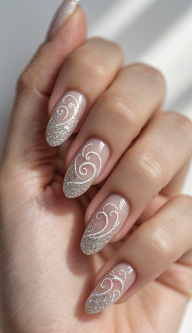 Almond-shaped nails with swirl nail art idea using nude base, silver glitter gradients, and white swirl line details held in a relaxed hand pose.