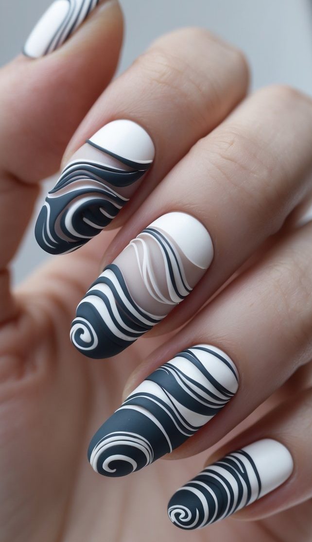 Swirl nail art idea with black and white matte nails featuring layered, high-contrast swirl designs and clear negative space detailing.