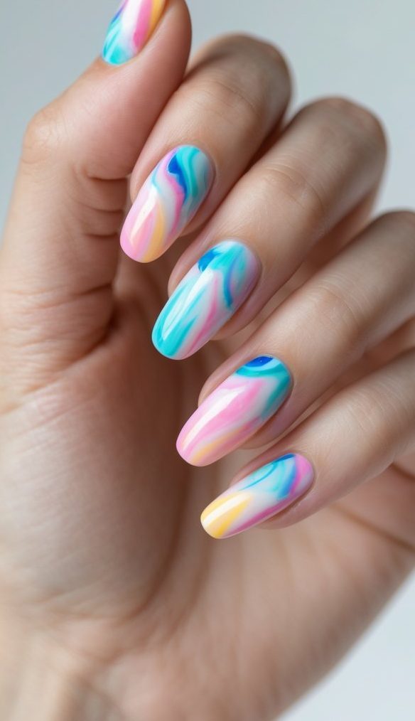 Close-up of fingernails with a tie dye nail art idea using blended pastel hues like peach, blue, and lavender in soft, melting wave patterns.