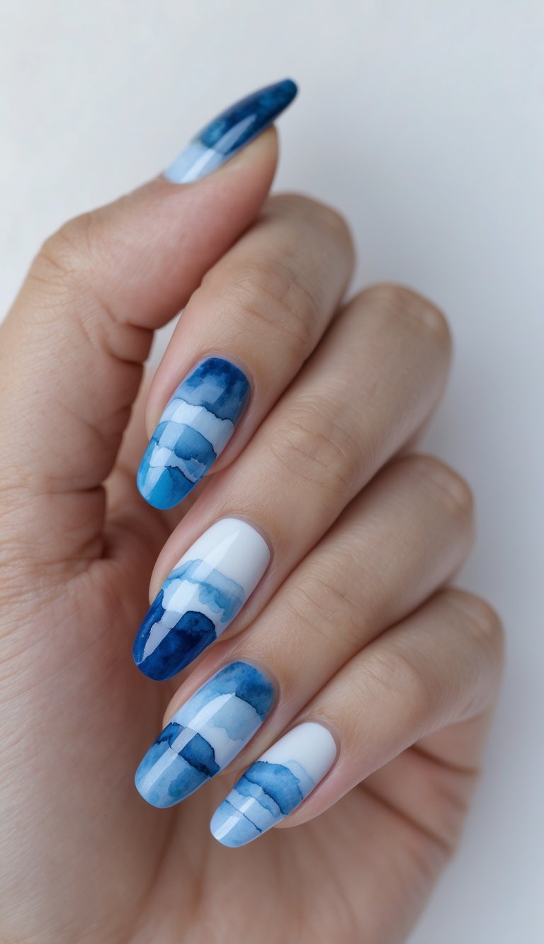 Glossy nails with watercolor stripe patterns in mixed blue shades, laid over white polish for a crisp and fluid watercolor nail art idea.