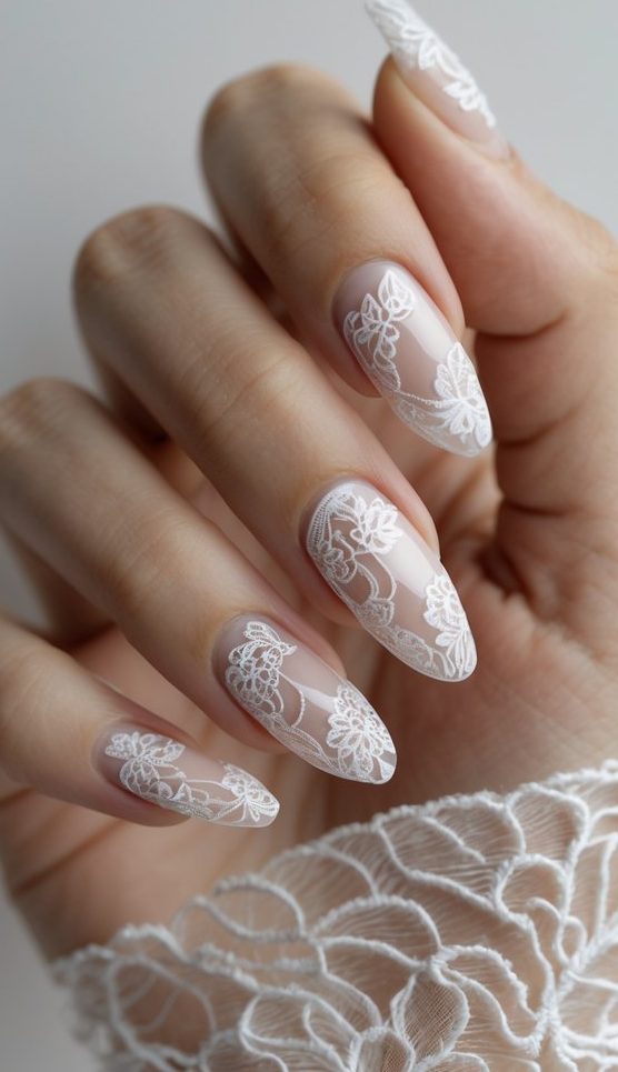 Feminine hand with transparent blush-toned nails adorned with delicate white floral lace, evoking a soft, romantic lace nail art idea.