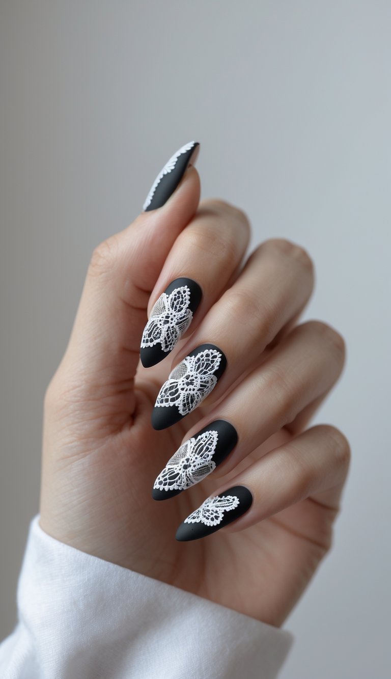 Hand with matte black stiletto nails featuring white floral lace nail art idea overlay, creating a bold and elegant monochrome contrast.