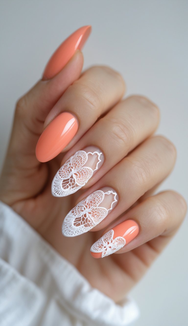 Hand with a lace nail art idea showing almond-shaped peach-orange nails with intricate white lace butterfly designs on the middle and ring fingers.
