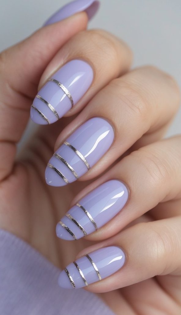 Oval nail art idea shown on a hand with glossy lilac nails, each nail divided into sections by thin silver metallic stripes for a minimal glam look.