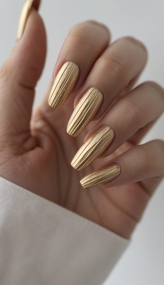 Close-up of long metallic nails with fine vertical texture and a reflective gold sheen—a sleek long nail art idea.