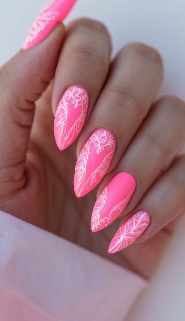 Hot pink nails featuring detailed white lace-like designs, creating a vibrant and ornate long nail art idea.