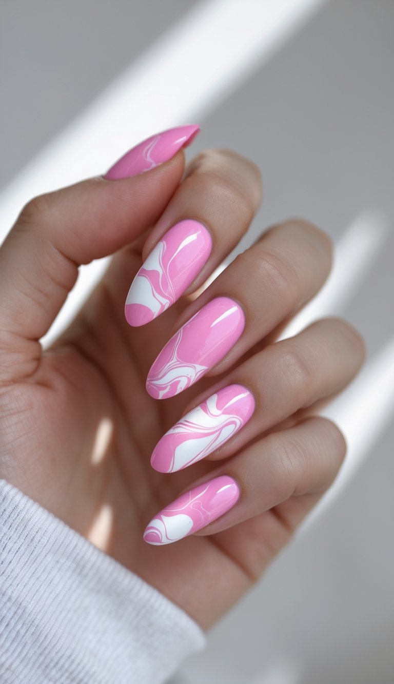 Barbiecore nail art idea featuring almond-shaped nails with a pink and white fluid marble design, shown on a hand against soft natural light in a minimal setting.