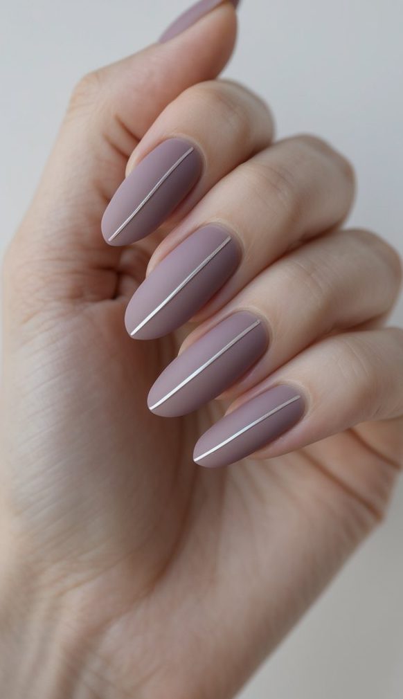 A hand styled with muted plum matte nails, each featuring a razor-straight silver stripe—an understated, editorial sophisticated nail art idea for minimal design lovers.