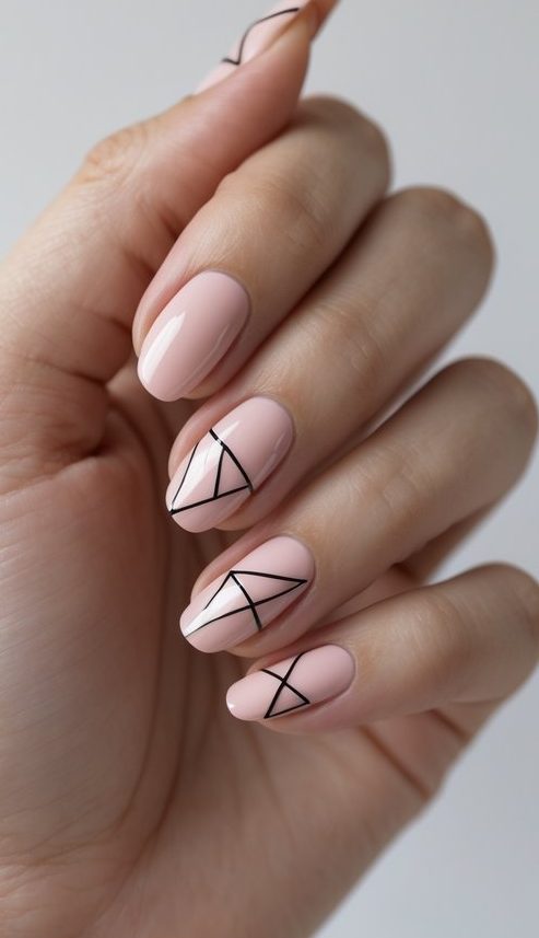 Almond nails painted in soft nude pink, layered with fine black triangle outlines—an artistic and contemporary sophisticated nail art idea with folded form.