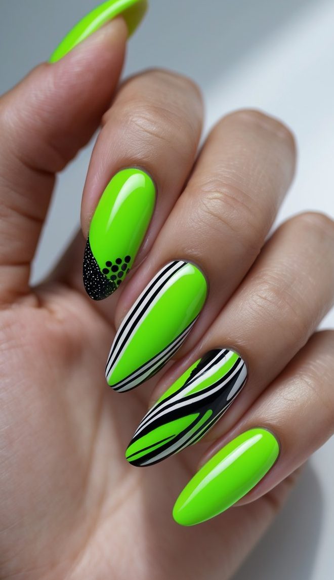 A stylish hand featuring a mix and match nail art idea with bright neon green polish, curved black-and-white striping, and fine dotted black textures.