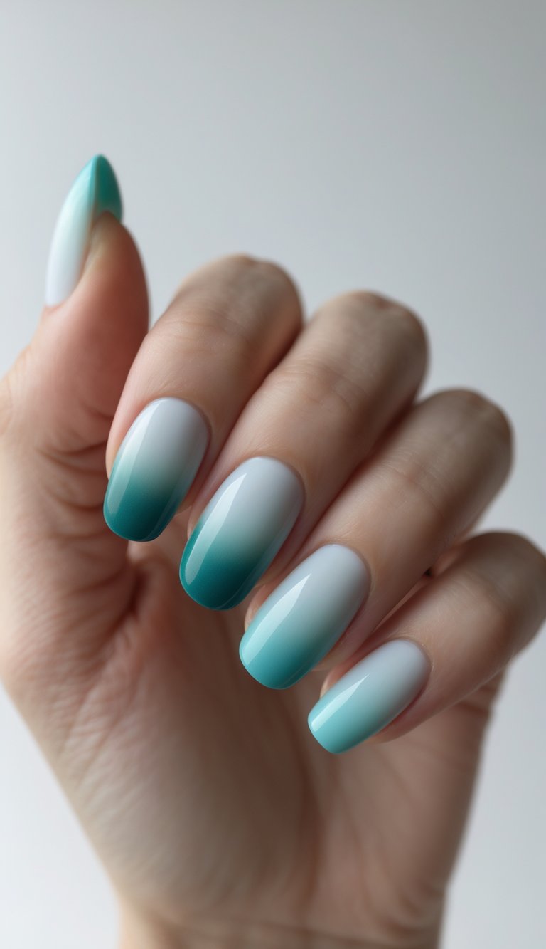 A hand with ombre nail art ideas featuring a turquoise-to-white gradient on long, glossy oval nails.