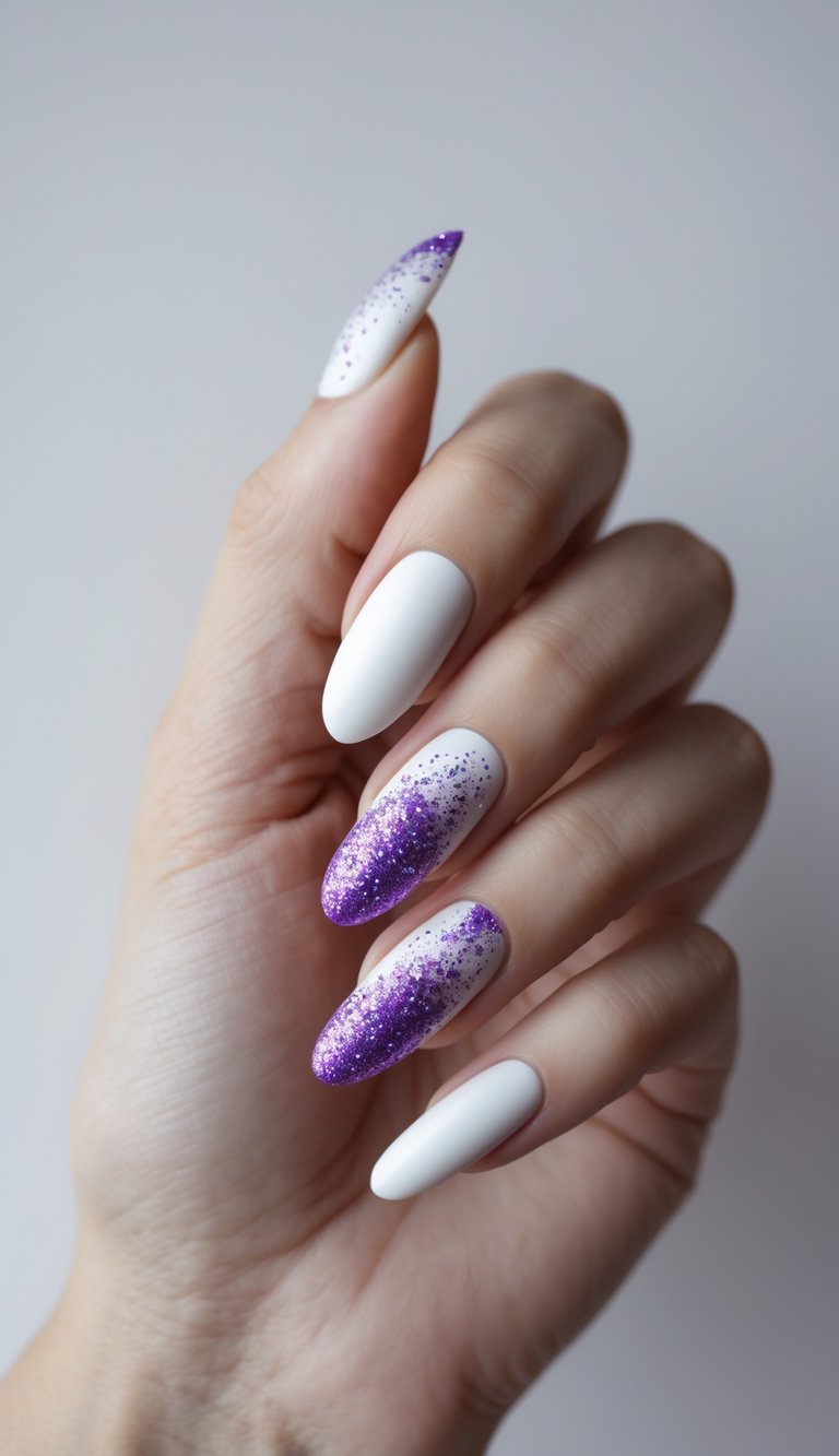 A hand with long almond nails shows a purple and white nail art idea featuring matte white polish paired with purple glitter gradients concentrated toward the tips.