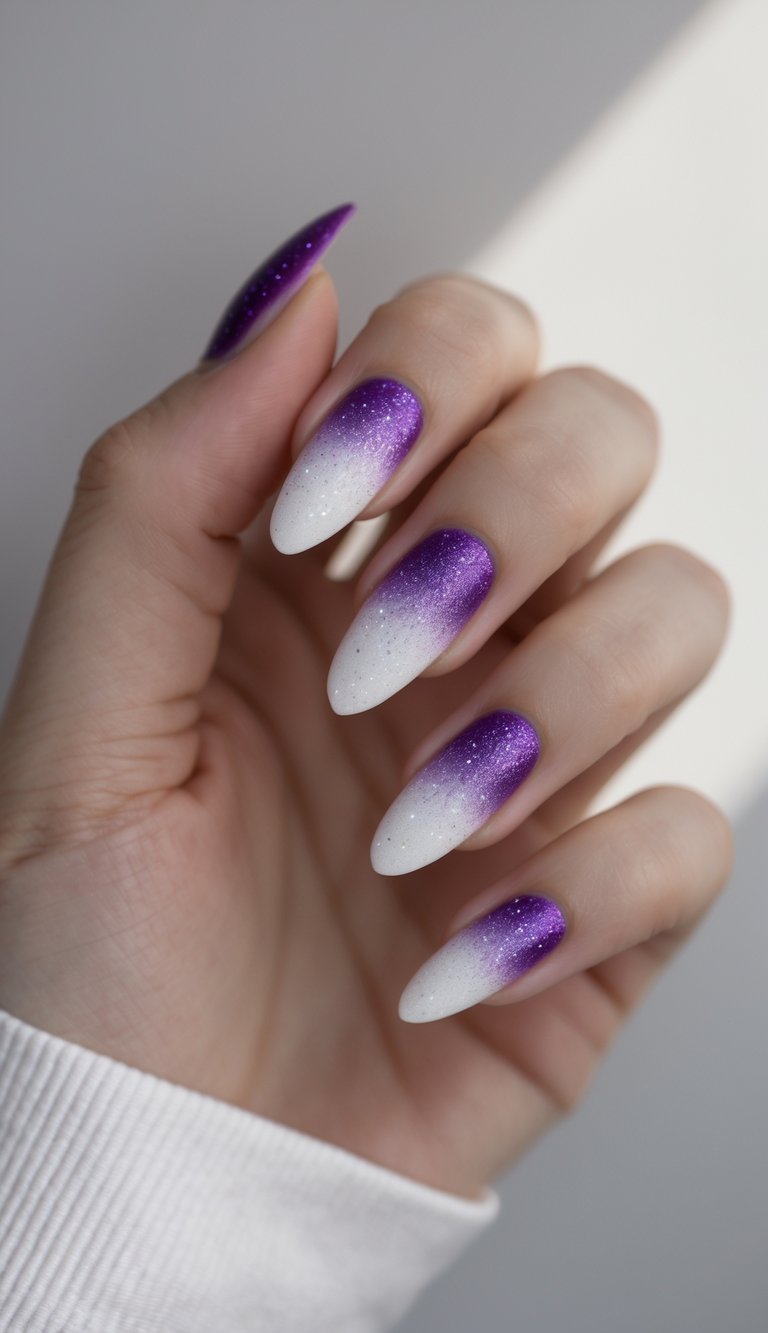 A hand with almond-shaped nails featuring a purple glitter ombré that melts into white tips, presenting a purple and white nail art idea with a luminous effect.